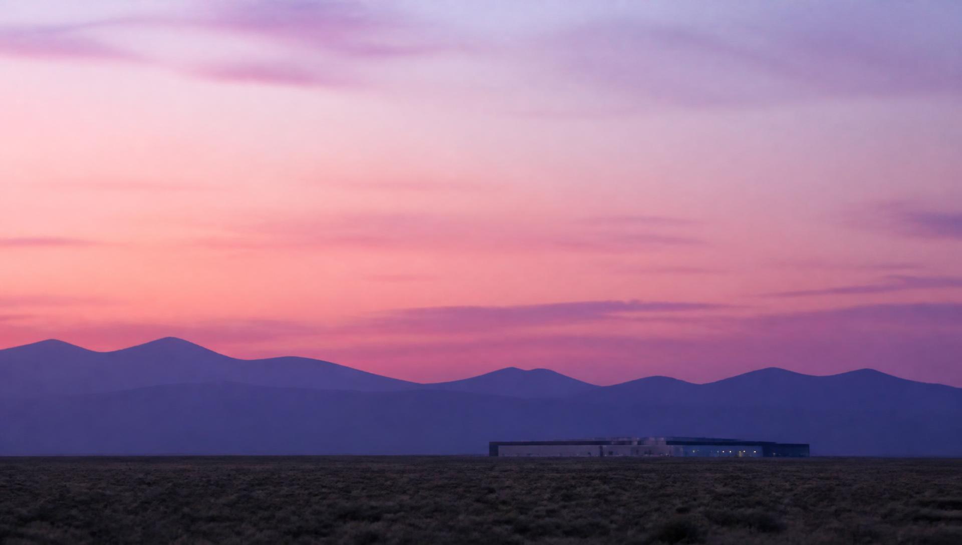 Sunset over mountains with a data center in the distance